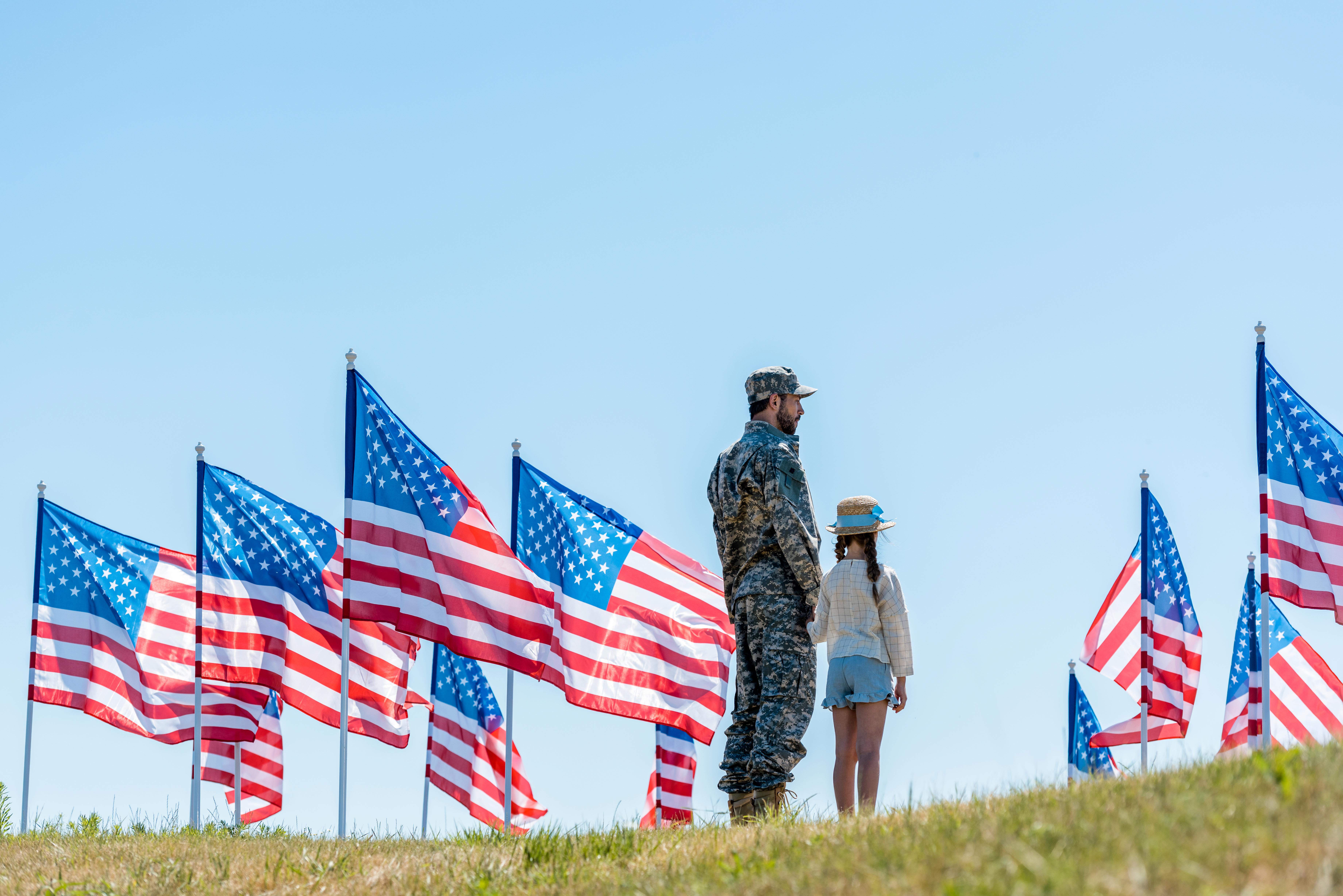 Picture of a father and daughter standing on a hill surrounded by American flags